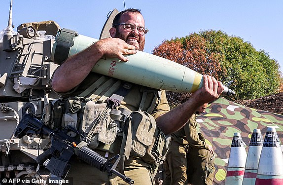 An Israeli soldier reacts while transporting a 155mm artillery shell near a self-propelled howitzer deployed at a position near the border with Lebanon in the upper Galilee region of northern Israel on October 18, 2023. Israeli troops killed four militants attempting to infiltrate from Lebanon, the army said on October 17, as tensions run high along the border between the two countries. (Photo by Jalaa MAREY / AFP) (Photo by JALAA MAREY/AFP via Getty Images)