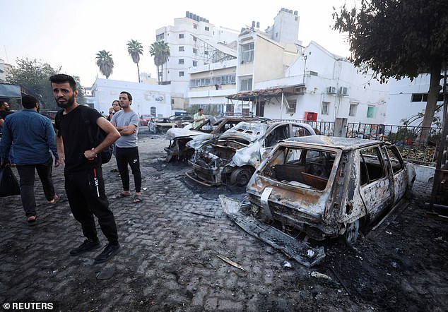 People inspect the area of Al-Ahli hospital where hundreds of Palestinians were killed in a blast that Israeli and Palestinian officials blamed on each other