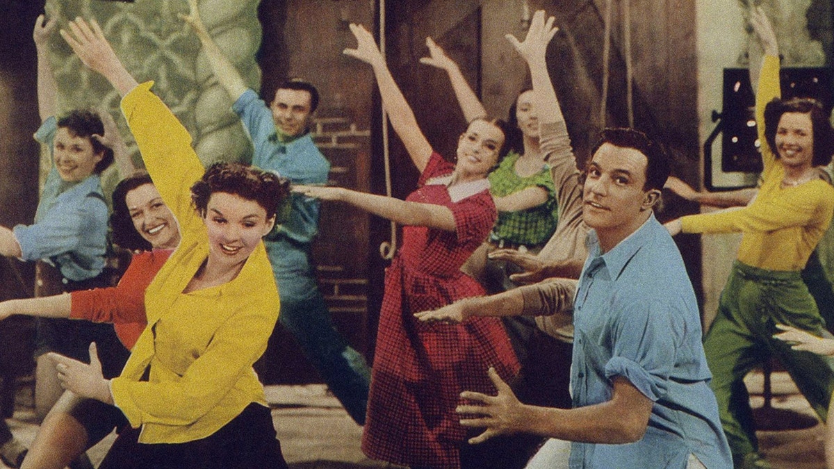 Schauspieler wie Judy Garland und Gene Kelly tanzen in bunten Hemden