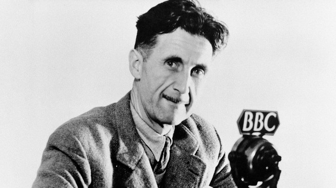 Ein Schwarz-Weiß-Porträt von George Orwell im Jahr 1943 vor einem Mikrofon mit einem "BBC" Etikett