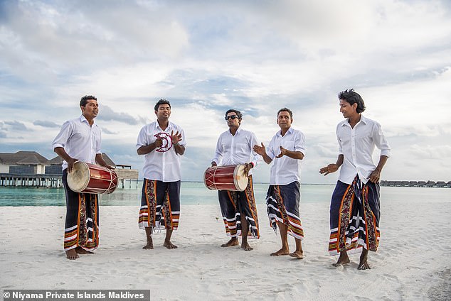 Oben spielen Musiker Boduberu-Trommeln und tanzen am Strand des Niyama-Resorts