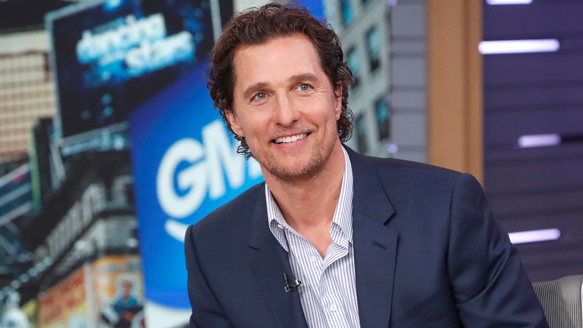 Matthew McConaughey lächelt bei GMA in einem blau gestreiften Hemd und einer dunkelblauen Blazerjacke
