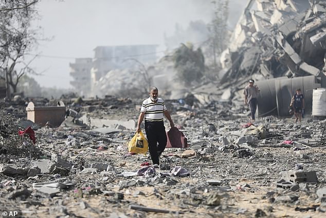 Palestinians walk by buildings destroyed in the Israeli bombardment on al-Zahra, on the outskirts of Gaza City, on Friday
