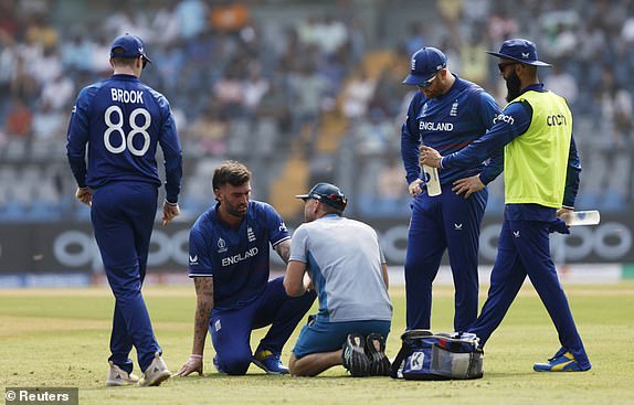 Cricket - ICC Cricket World Cup 2023 - England v South Africa - Wankhede Stadium, Mumbai, India - October 21, 2023 England's Reece Topley receives medical attention after sustaining an injury REUTERS/Francis Mascarenhas