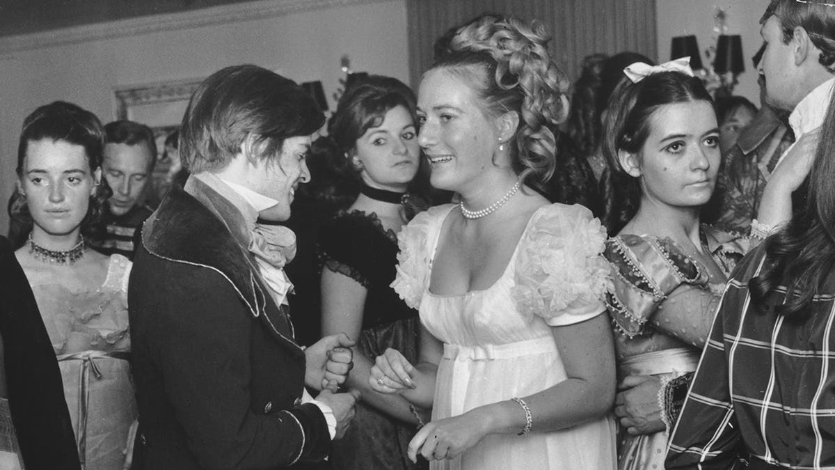 Eine Nahaufnahme von Prinzessin Olga Romanoff in einem weißen Kleid, umgeben von Menschen