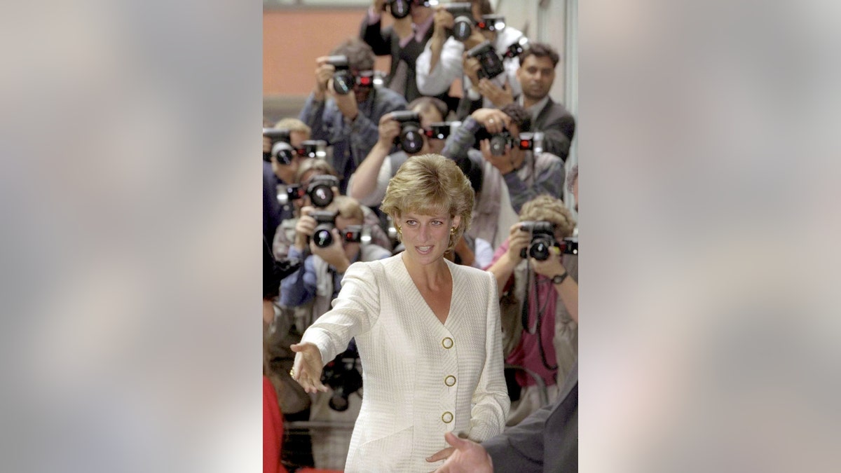 Prinzessin Diana trägt einen elfenbeinfarbenen Anzug, während Fotografen sie umgeben