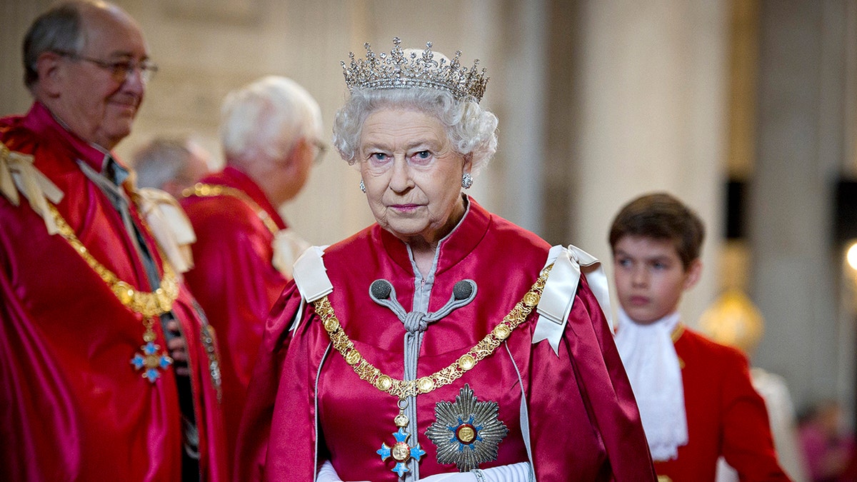 Königin Elizabeth II. trägt ein rotes Kleid und eine Krone