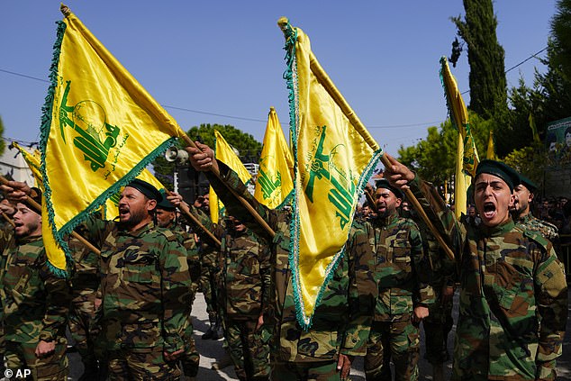 Hezbollah fighters rise their group's flag and shout slogans, as they attend the funeral procession of Hezbollah fighter, Bilal Nemr Rmeiti