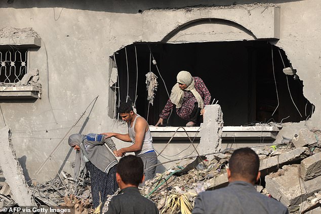 A Palestinian man helps evacuate a woman from a damaged building after overnight Israeli strikes on Rafah in the southern Gaza Strip on October 22