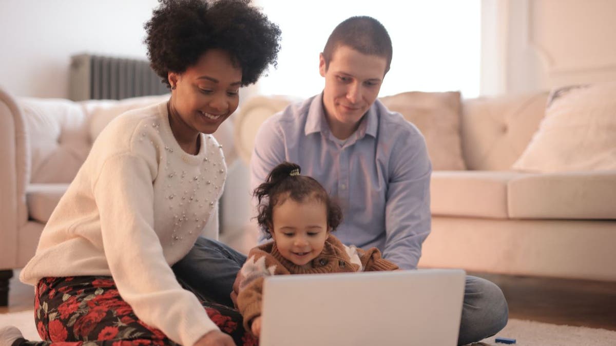 Tochter mit Eltern schaut auf Laptop