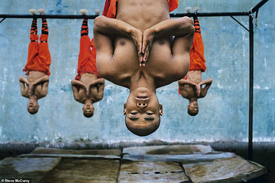 Dieses farbenfrohe Bild aus dem Jahr 2004 zeigt Mönche, die an einem Metallbalken in der Shaolin-Kampfkunstschule in Zhengzhou, China, hängen