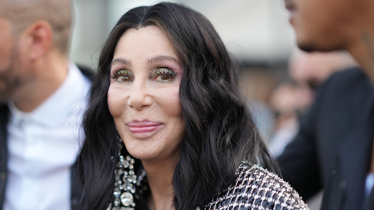 Cher lächelt sanft in einem karierten Mantel in Paris, Frankreich