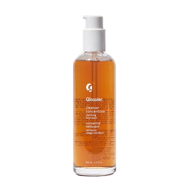 Glossier Cleanser Concentrate in Pumpflasche mit orangefarbenem Inhalt auf weißem Hintergrund