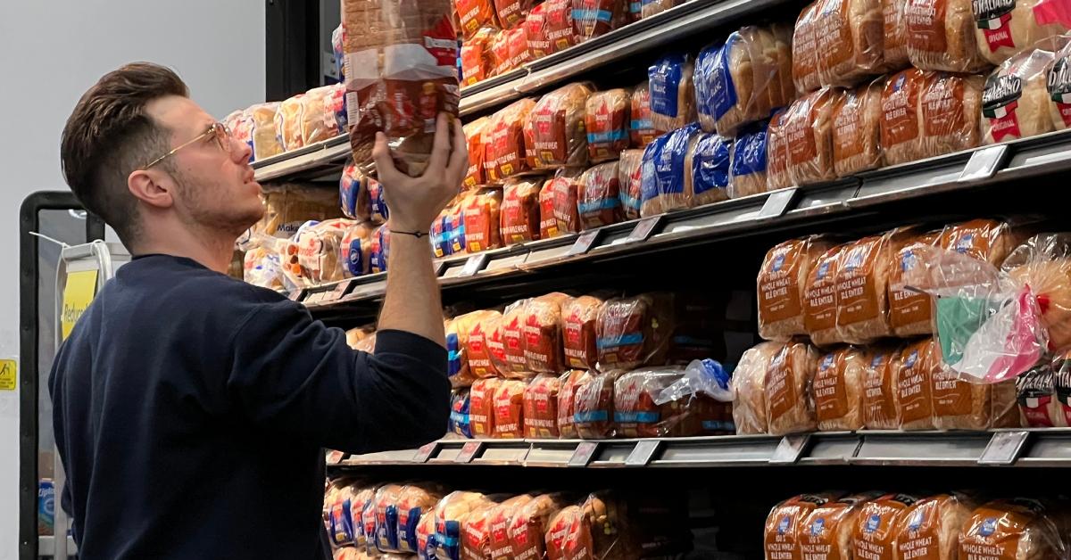 Ein Mann sucht in einem Lebensmittelgeschäft einen Laib Brot aus