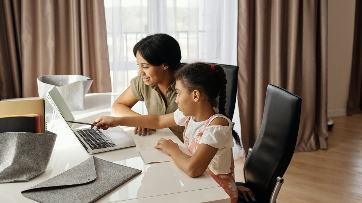 Mutter und Tochter sitzen zusammen und schauen auf den Laptop