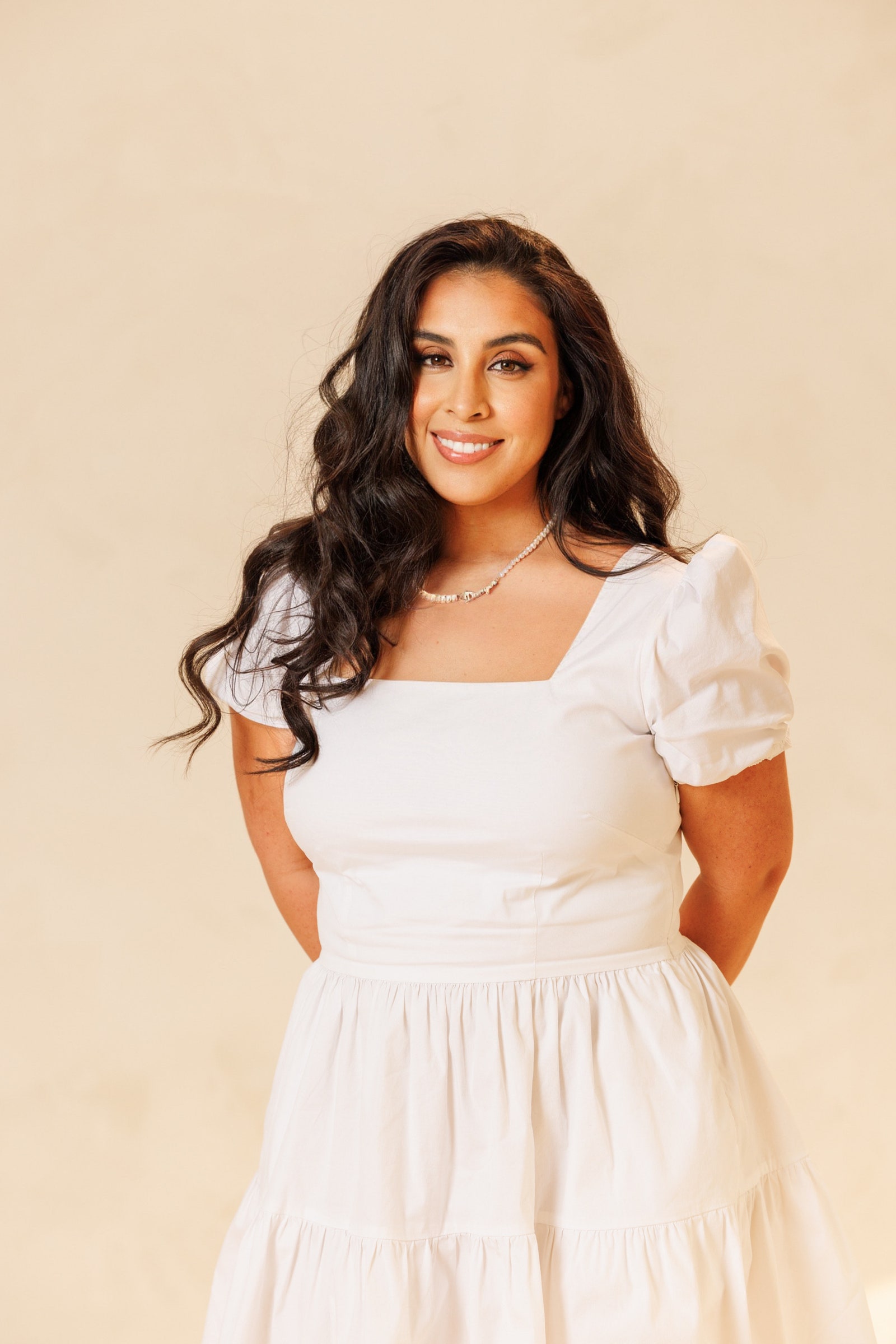Kopfbild von Stephanie Montes auf hellbraunem Hintergrund in einem weißen Kleid