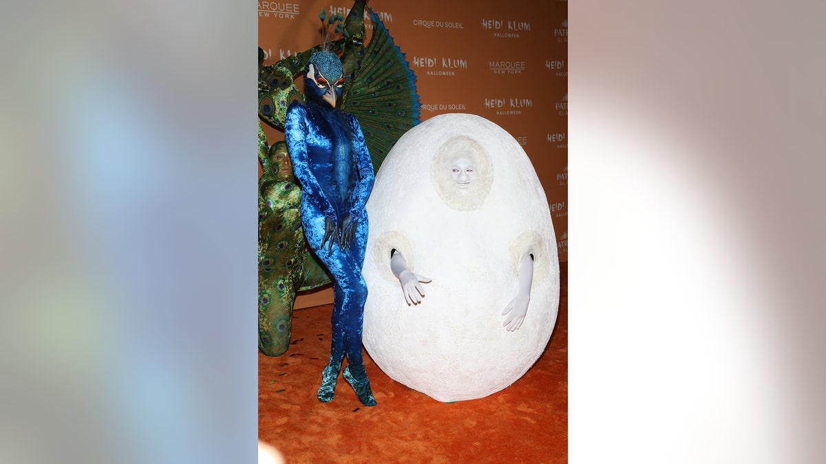 Heidi Klum als Pfau verkleidet neben ihrem als Ei verkleideten Mann