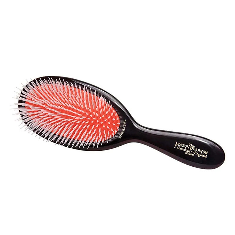 Mason Pearson Haarbürste mit Nylonborsten in Junior-Größe: Eine schwarze Haarbürste mit roter Borstenpolsterung und weißen Borsten auf weißem Hintergrund
