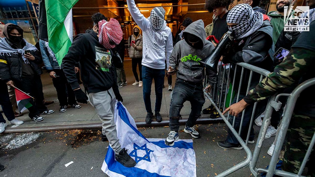 Man sieht einen Demonstranten auf der israelischen Flagge herumtrampeln