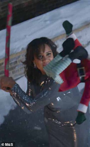 Zawe Ashton is suddenly on the roof of her home, going full Tarantino in her sequins, using a roll of wrapping paper like a baseball bat to whack a blameless elf across the city skyline