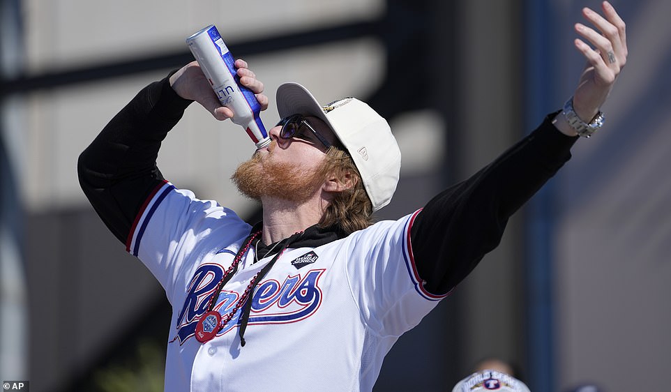 Rangers-Pitcher Jon Gray trinkt vor den Fans ein Michelob-Ultra-Bier, während er bei der Parade auf der Ladefläche eines Pickups fährt