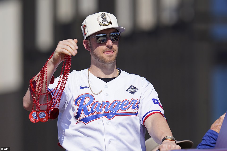 Rangers-Fänger Mitch Garver warf den Fans Perlenketten zu, während er während der Parade am Freitag in der texanischen Sonne badete