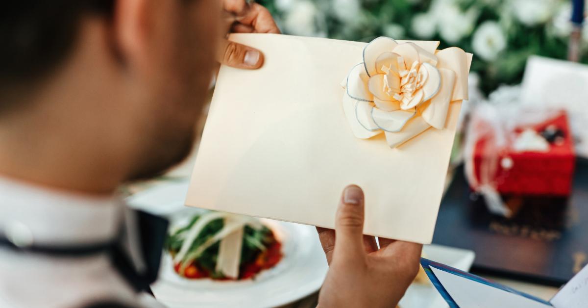 Ein Bräutigam hält nach seiner Hochzeitszeremonie eine Karte in der Hand.