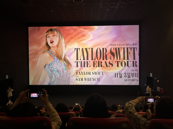 Fans von Taylor Swift machen Fotos vor der Postervorführung vor der Premiere von „Taylor Swift: The Eras Tour“ im CGV Yongsan am Freitag. [SHIN MIN-HEE]