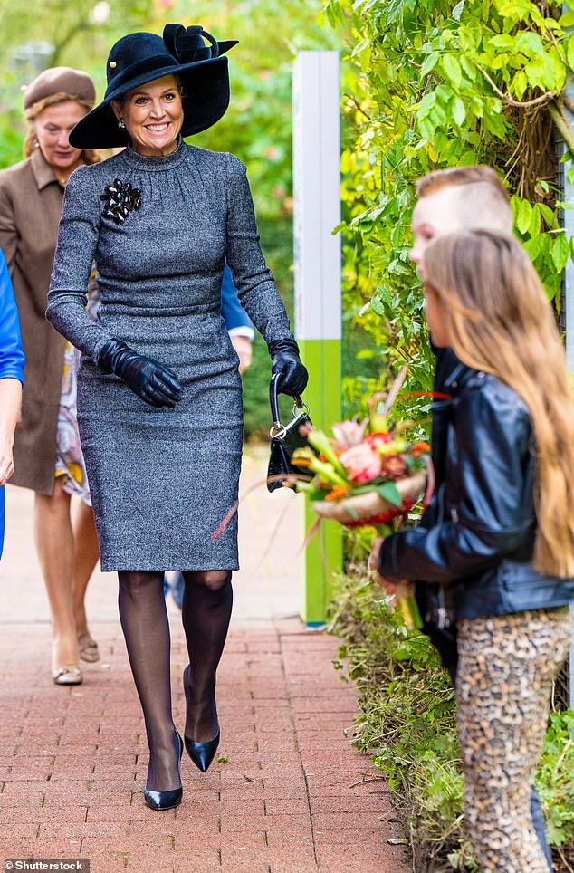 Herbstlich gekleidet, mit einem Hut mit breiter Krempe, wurde sie von zwei Kindern begrüßt, die sie mit einem Strauß bunter Blumen begrüßten
