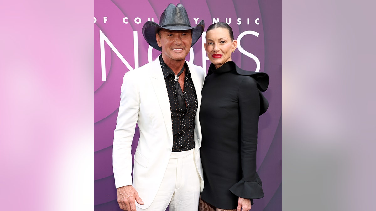 Tim McGraw posiert in weißer Jacke, schwarzem Hemd und schwarzem Cowboyhut mit Faith Hill in einem schwarzen Rüschenkleid auf dem Teppich