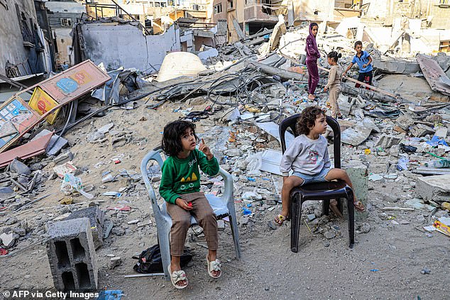 Palestinian children sit in front of the rubble of a destroyed building in Rafah in the southern Gaza Strip on November 6, 2023