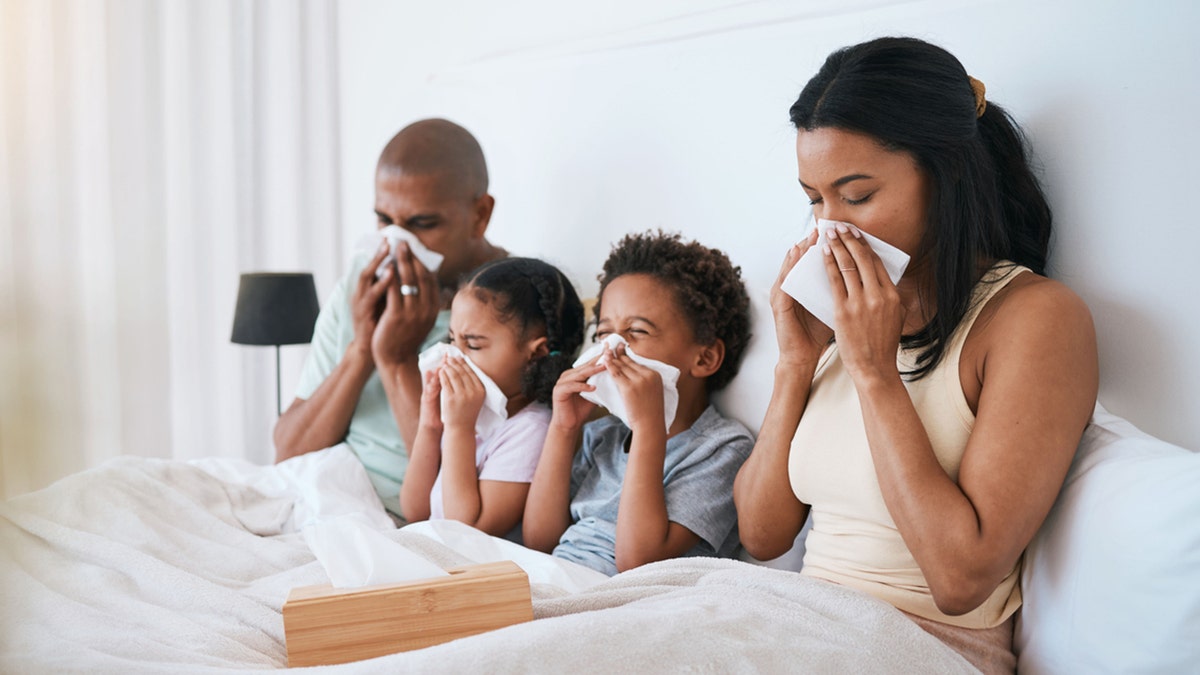Familie liegt mit Grippe im Bett