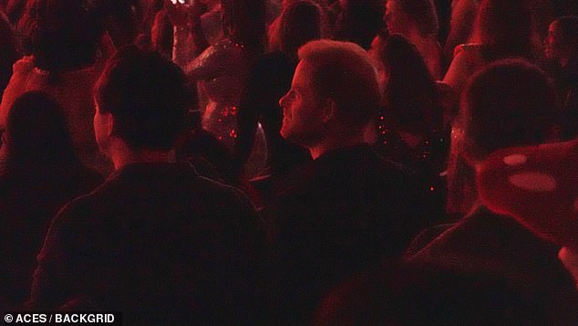 Prince Harry looks attentively at the stage as the lights get turned down for the concert