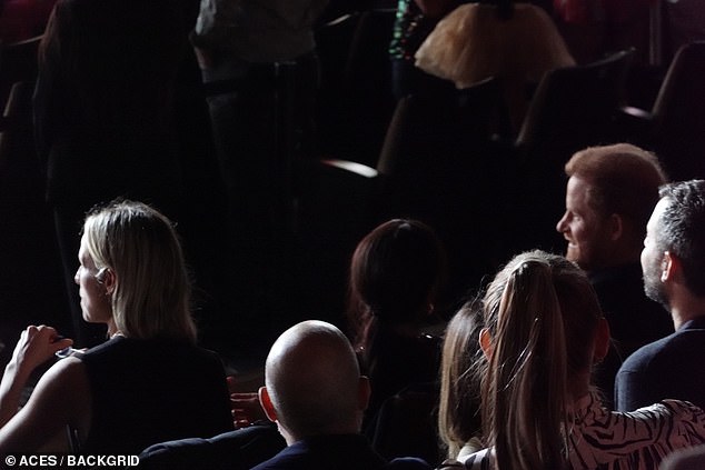 Prince Harry can be seen smiling as Meghan looks in his direction at one point duirng the concert