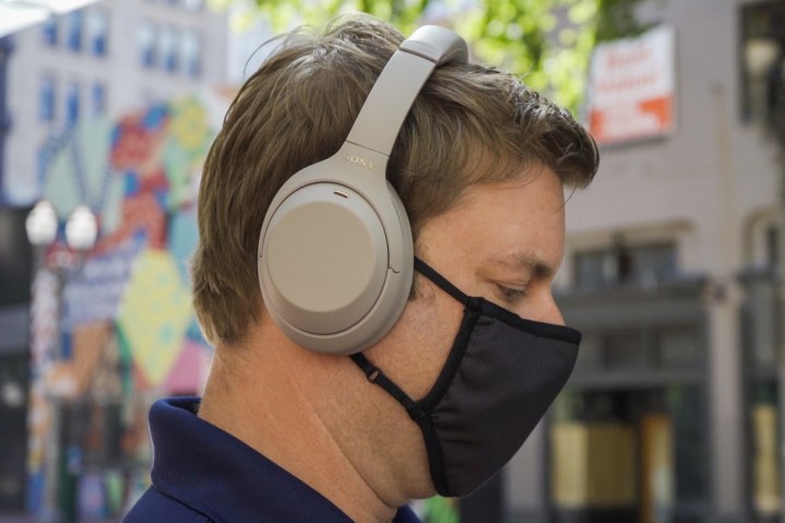 Ein Mann mit Maske und Sony WH 1000XM4-Kopfhörern.