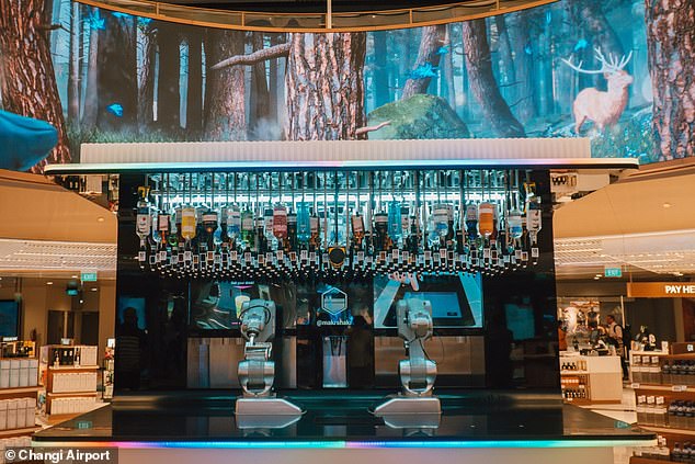 Passagiere können sich im neuen zweistöckigen Lotte Duty Free Wines & Spirits Store einen kostenlosen Cocktail vom „Roboter-Barkeeper“ des Terminals, Toni, holen