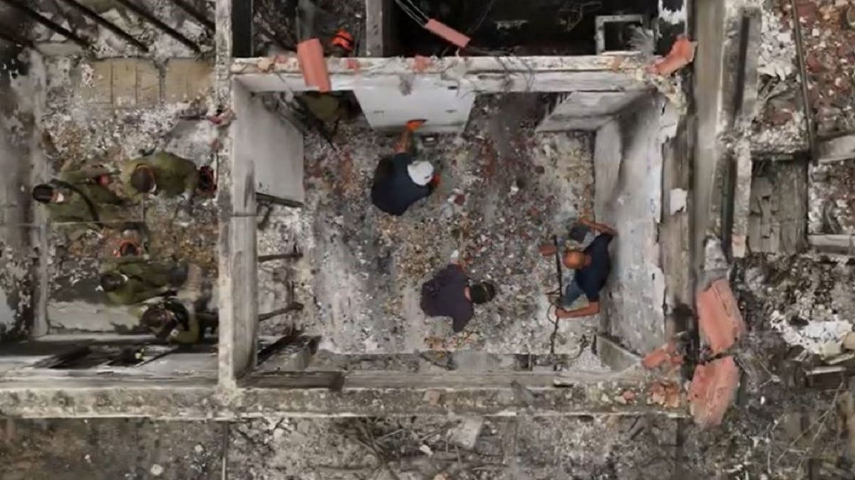 Luftaufnahme von Archäologen, die Trümmer in einem verbrannten Haus in Israel durchsuchen.