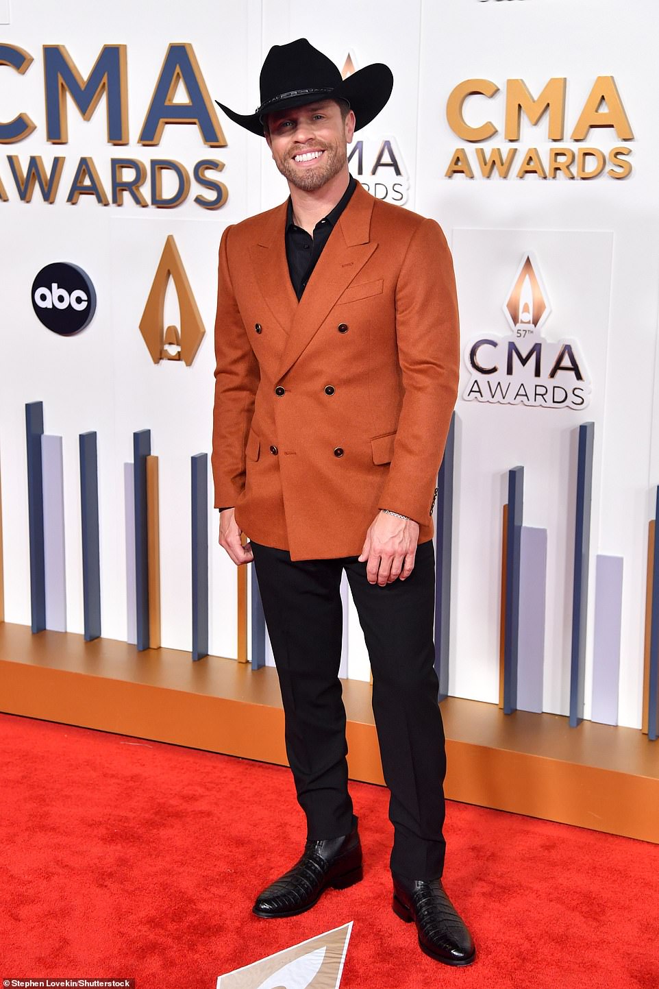 Country music's biggest night: Dustin Lynch looked handsome as he arrived to the red carpet in a burnt orange jacket, black cowboy hat and coordinating trousers
