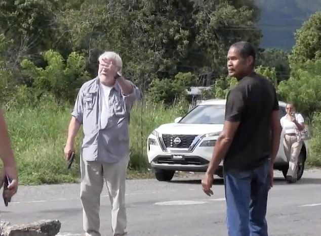 Darlington is seen in video of the incident gesturing with the handgun in his right hand, as he argues with the protesters blocking the road