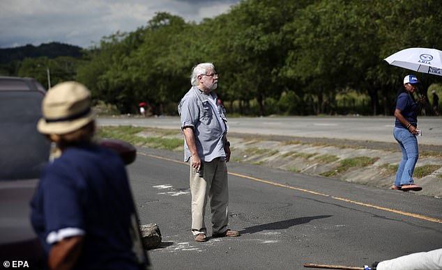 Darlington is seen standing in the middle of the road after being seen to have shot two people in the middle of the protest, sending bystanders running for cover
