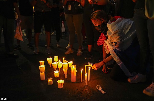 A woman draped in a Panamanian flag lights a candle during a Wednesday night vigil
