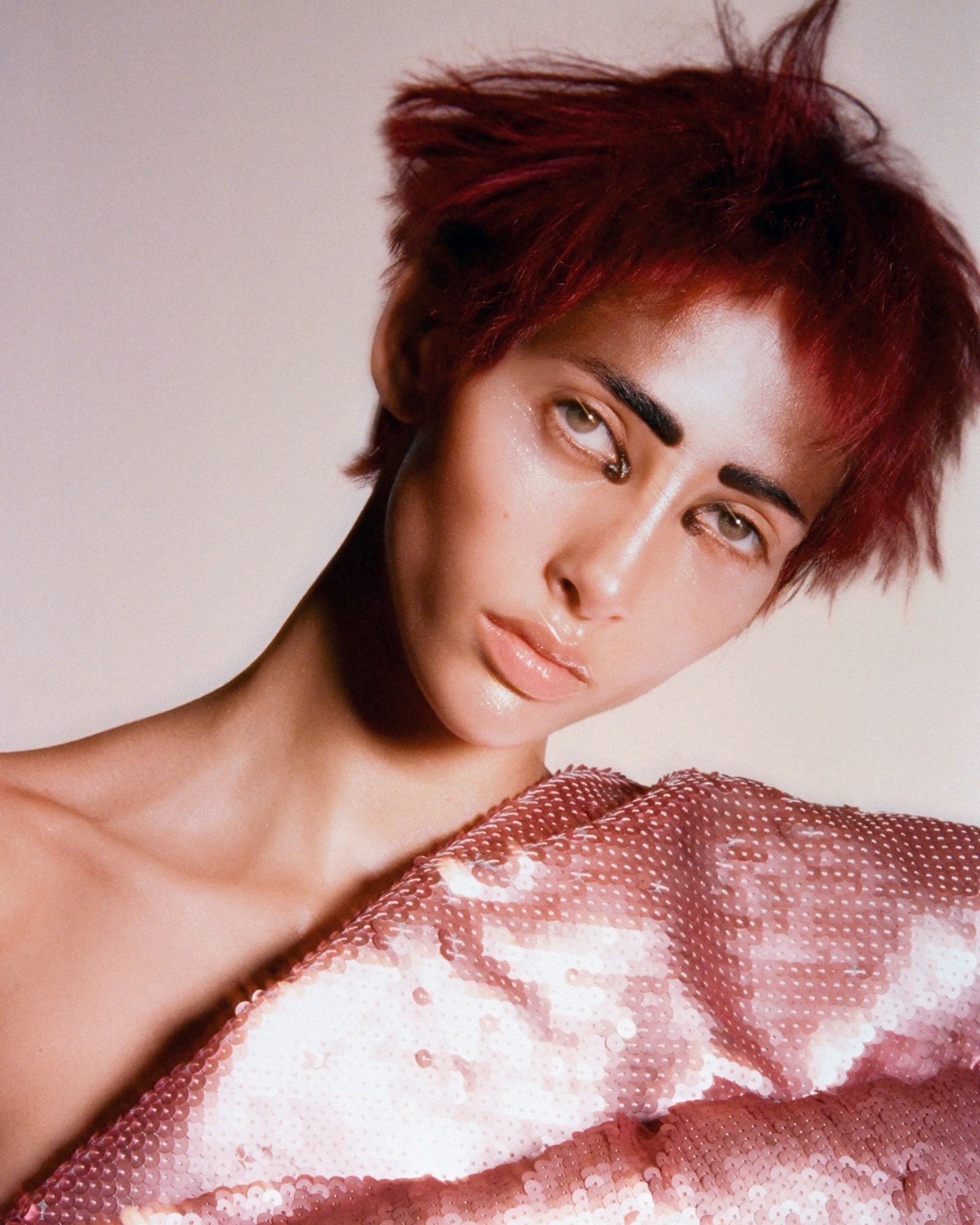 Make-up-Porträt mit roten Haaren, schwarzen Augenbrauen und einem rosa Paillettenoberteil
