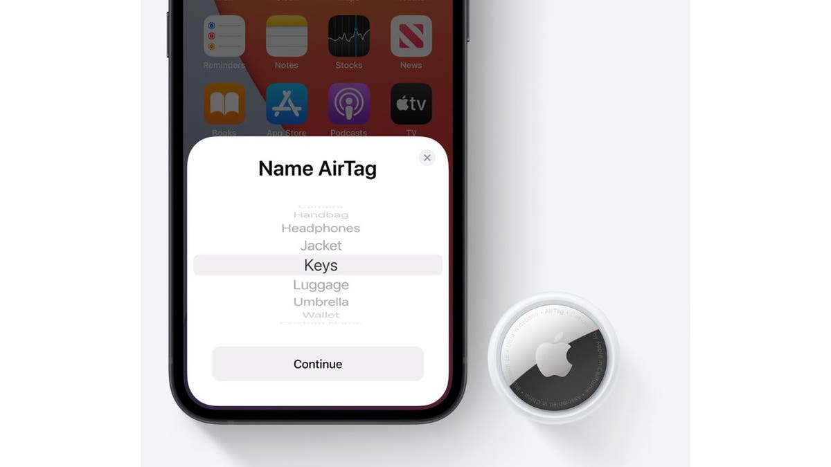 AirTag neben einem iPhone mit AirTag-Benachrichtigung auf dem Bildschirm