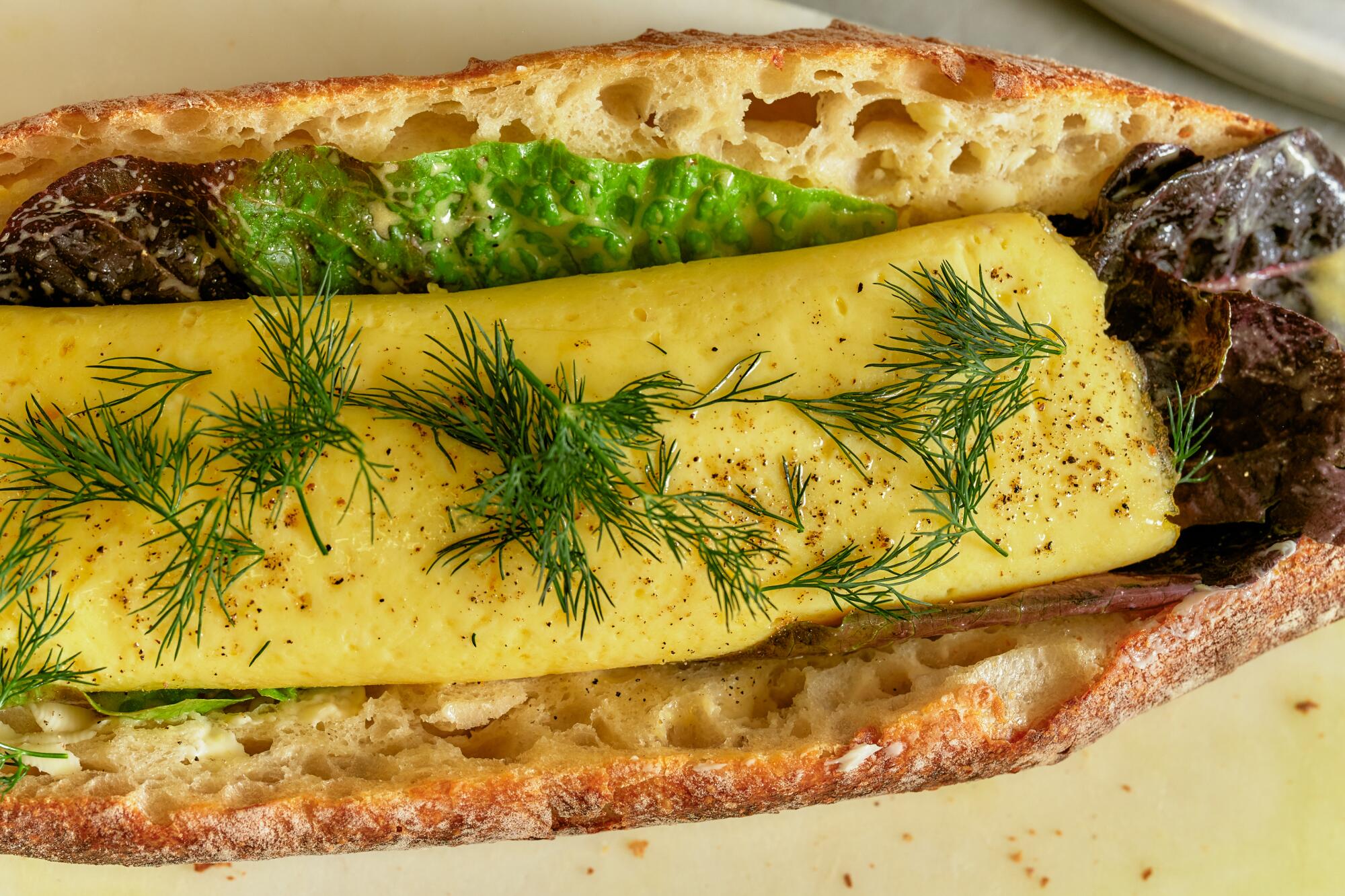 Ein geteiltes Baguette enthält ein mit Dill bestreutes Omelett