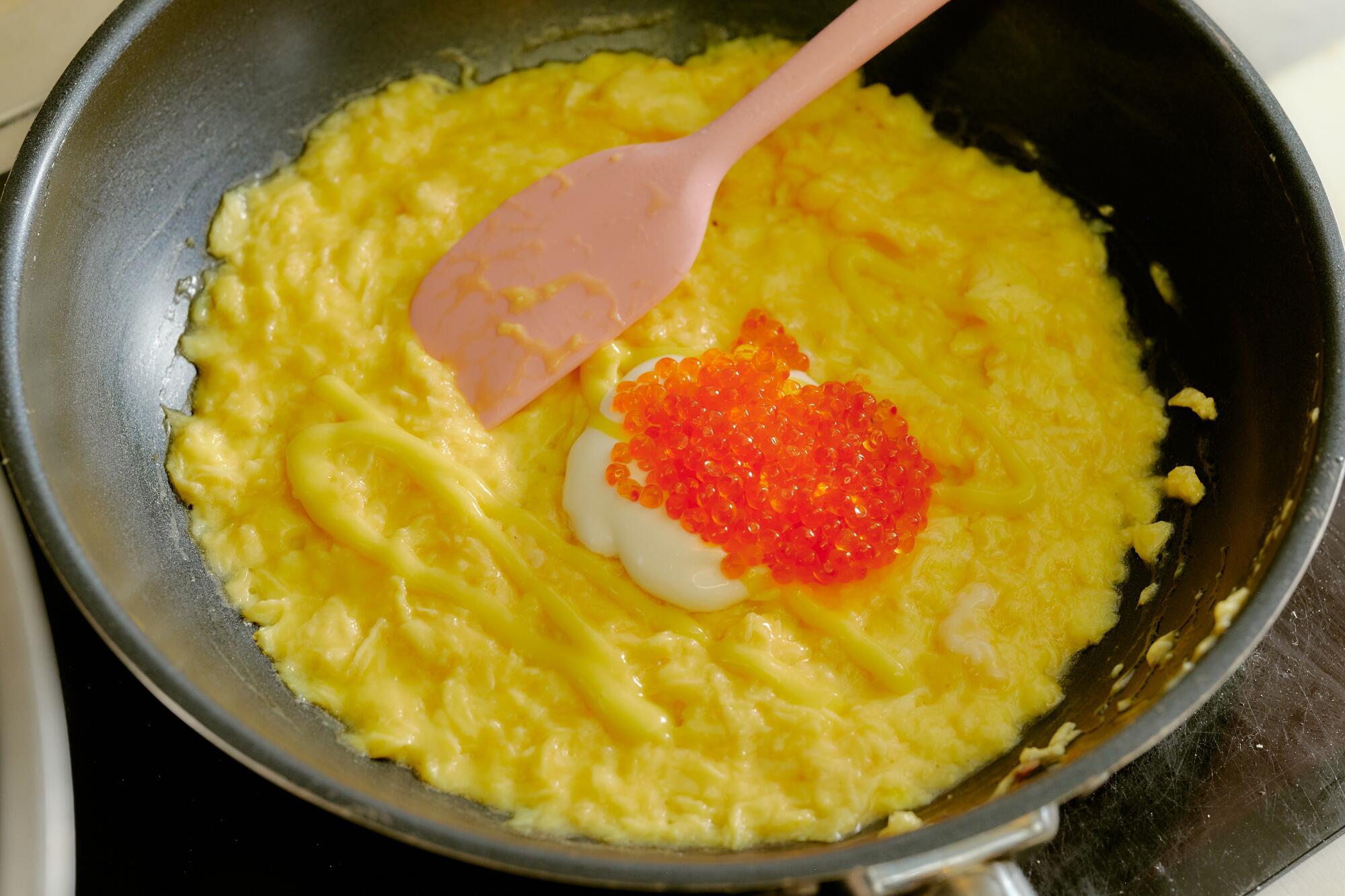 Ein französisches Omelett kocht in einer Pfanne, garniert mit Orangenrogen