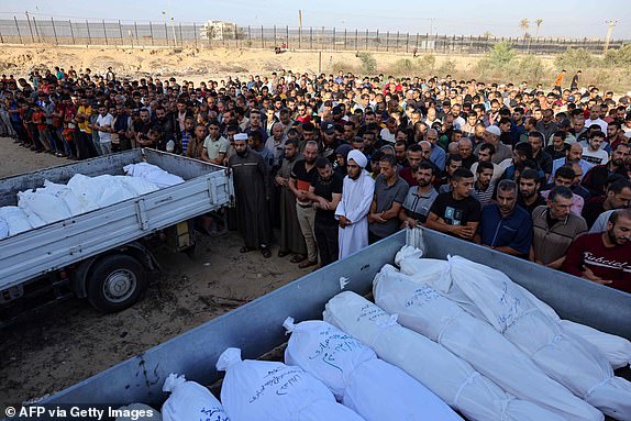 TOPSHOT - Palestinians pray near the bodies of members of the Hijazi family, killed in Israeli strikes in Rafah in the southern Gaza Strip before their burial on November 10, 2023, amid ongoing battles between Israel and the Palestinian group Hamas. More than 10,000 people have been killed across the Gaza Strip, according to the Hamas-run health ministry, since the war erupted after Hamas militants raided southern Israeli on October 7 killing at least 1400 people. (Photo by MOHAMMED ABED / AFP) (Photo by MOHAMMED ABED/AFP via Getty Images)