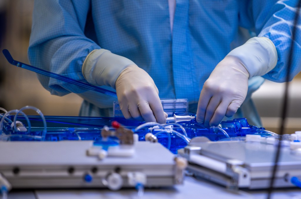 Ein Mitarbeiter prüft in einem Reinraum von Miltenyi Biotec die Dichtheit eines Schlauchsets, in dem Patientenzellen zu Medikamenten verarbeitet werden.