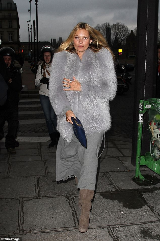 Der graue Kunstpelzmantel von Kate Moss, der über einem Kleid und Stiefeln getragen wird, verleiht ihrem Abendlook eine glamouröse Note