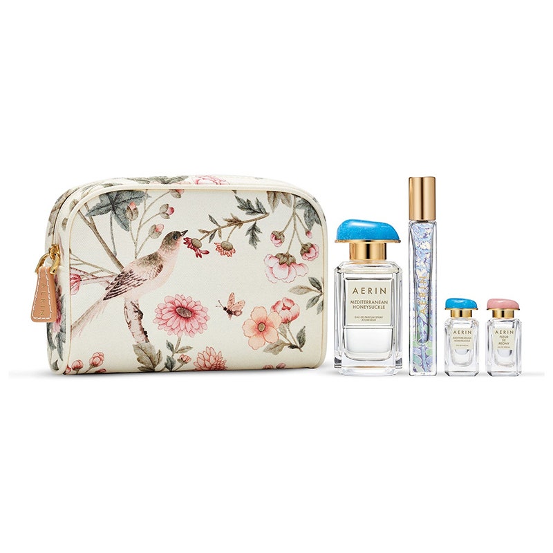Aerin Mediterranean Honeysuckle Summer Essentials Set: Eine Make-up-Tasche mit Blumenmuster und vier Parfümflaschen auf weißem Hintergrund