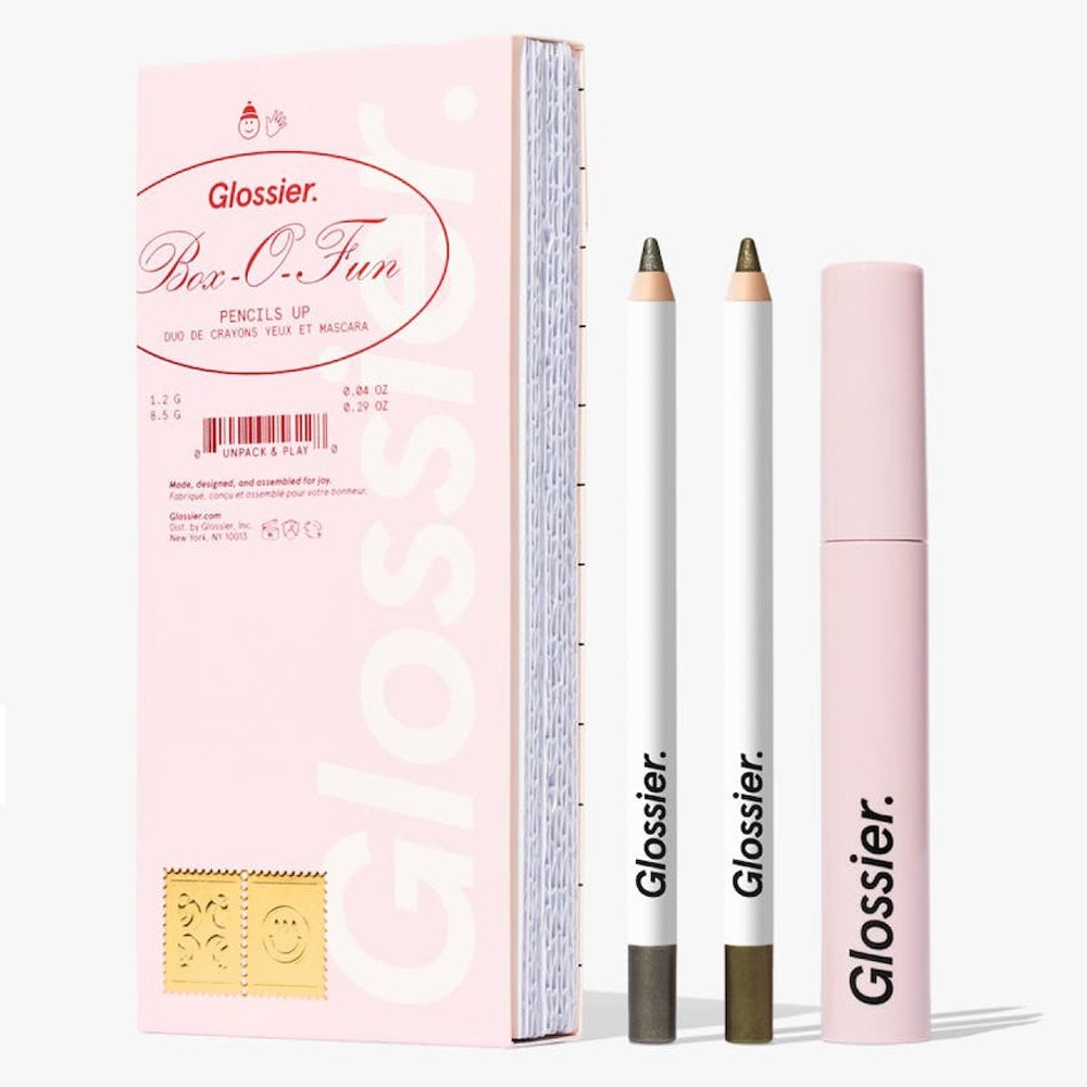 Glossier Pencils Up Kit, zwei Bleistifte, eine rosa Mascara-Tube und eine rosa Schachtel auf grauem Hintergrund